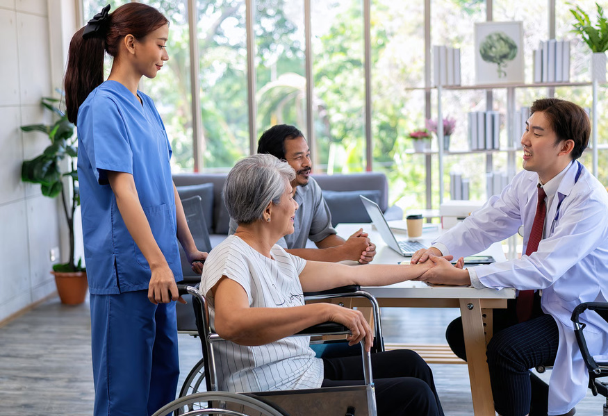 Male doctor checking the pulse of an elderly woman in a wheelchair during a medical checkup.
